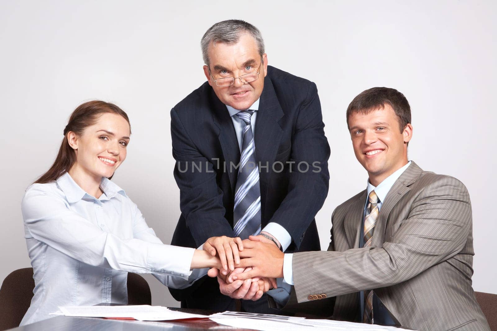 Photo of three partners putting their hands on the top
