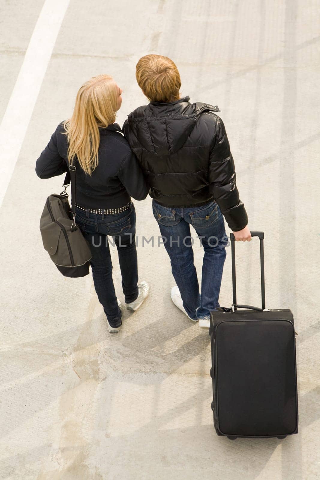 Above view of couple walking down trottoire with their baggage and chatting