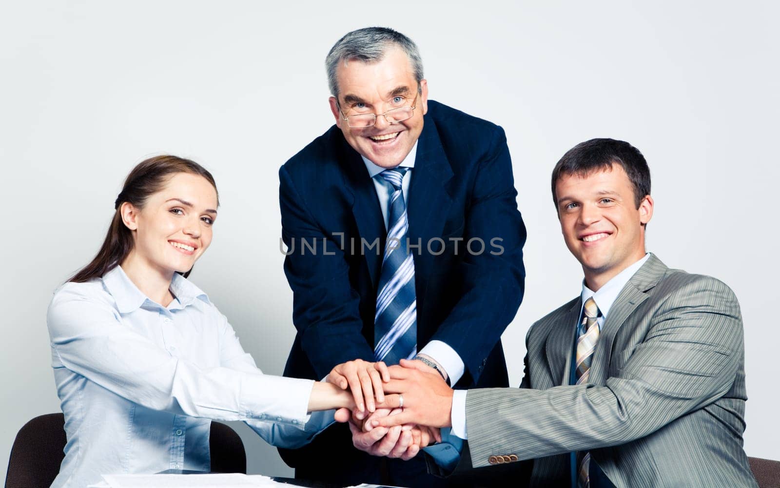 Photo of three partners putting their hands on the top