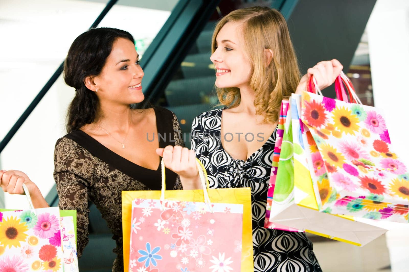 Portrait of two women looking at each other with smiles in the shopping mall