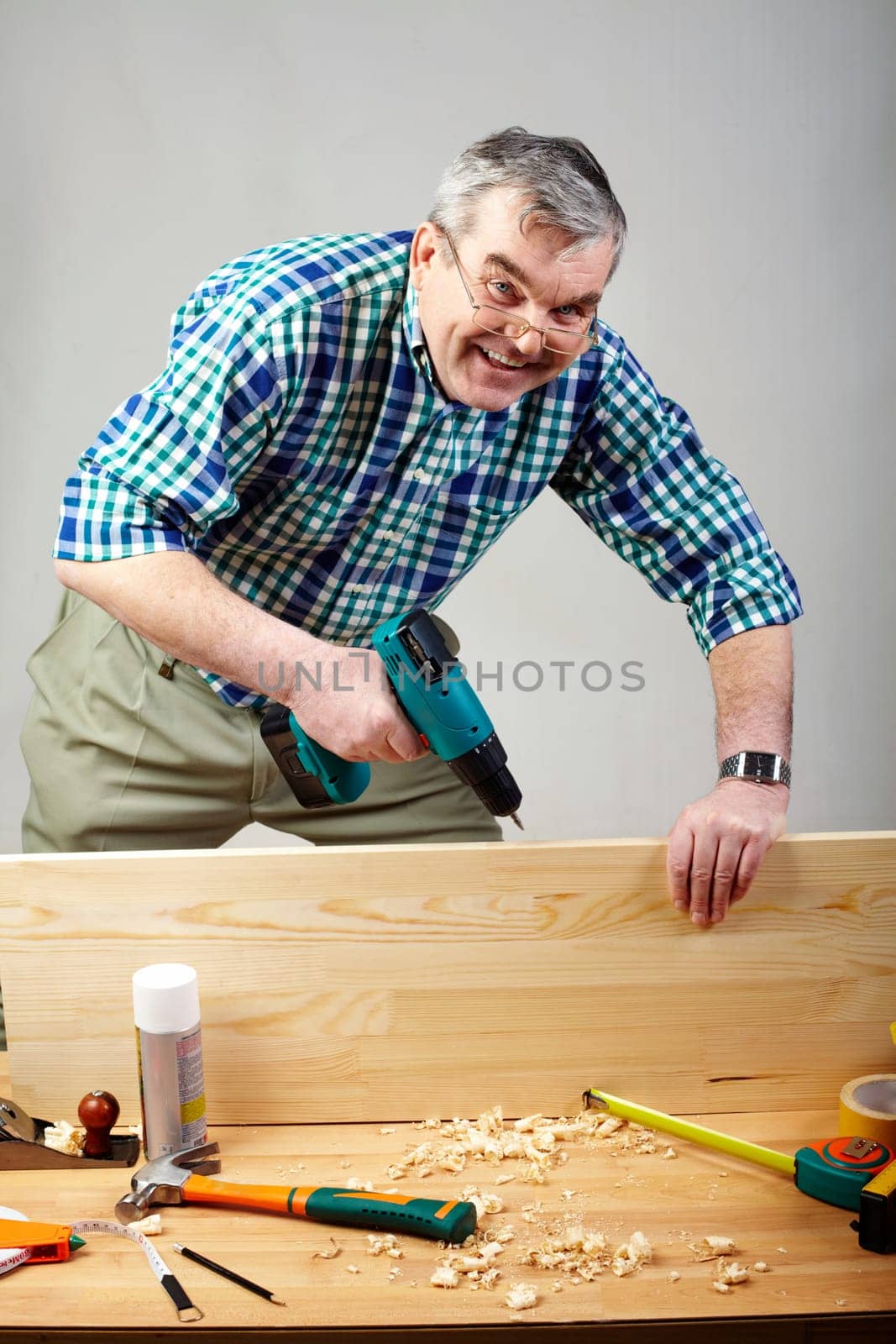 Senior man drilling plank in workshop