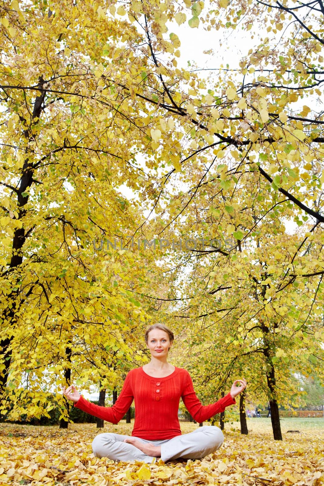 Young woman meditating outdoors in autumn park