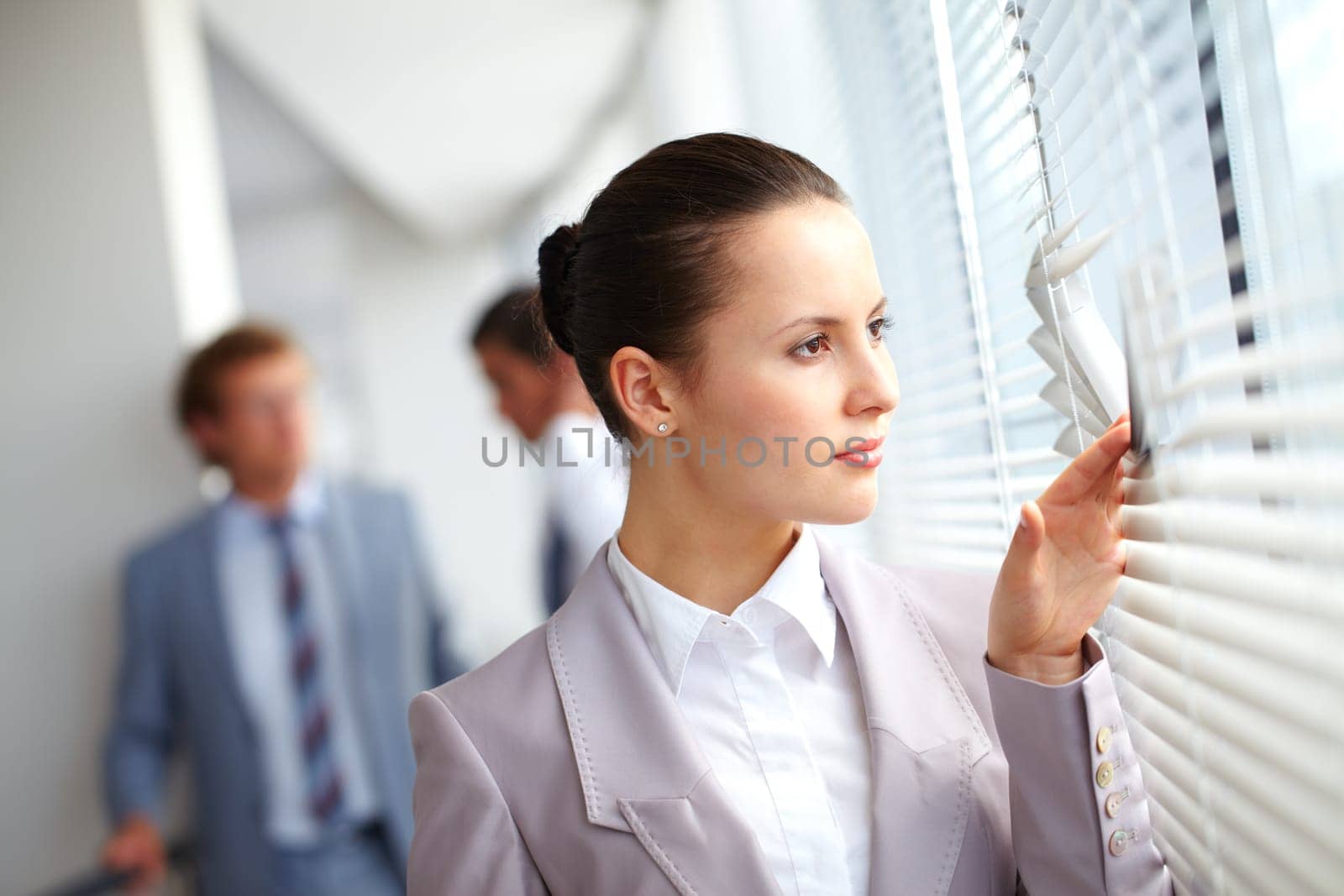 Businesswoman looking through window against her colleagues