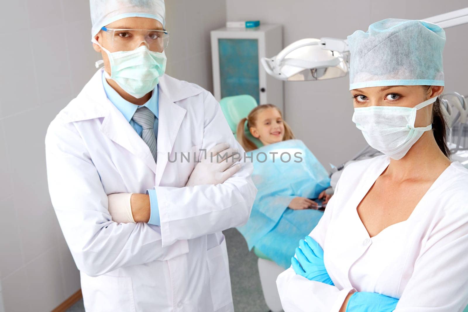 Portrait of pretty assistant and dentist in masks looking at camera in dentistry office