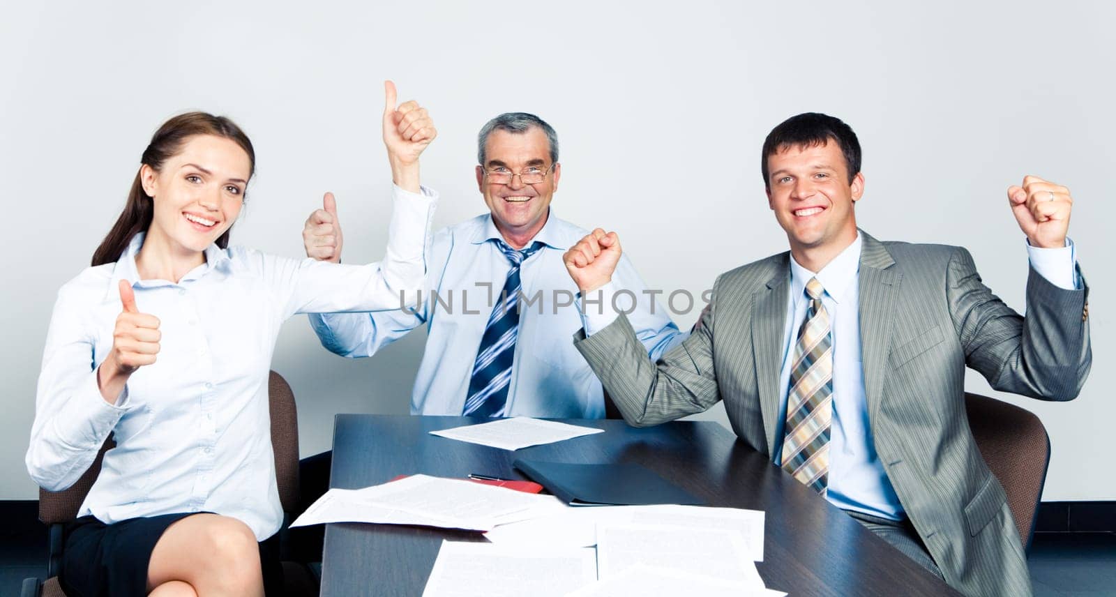 Team of three office workers showing a successful sign