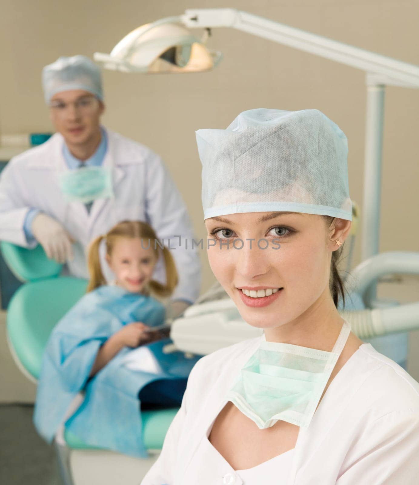 Portrait of young professional looking at camera on background of her colleague and patient