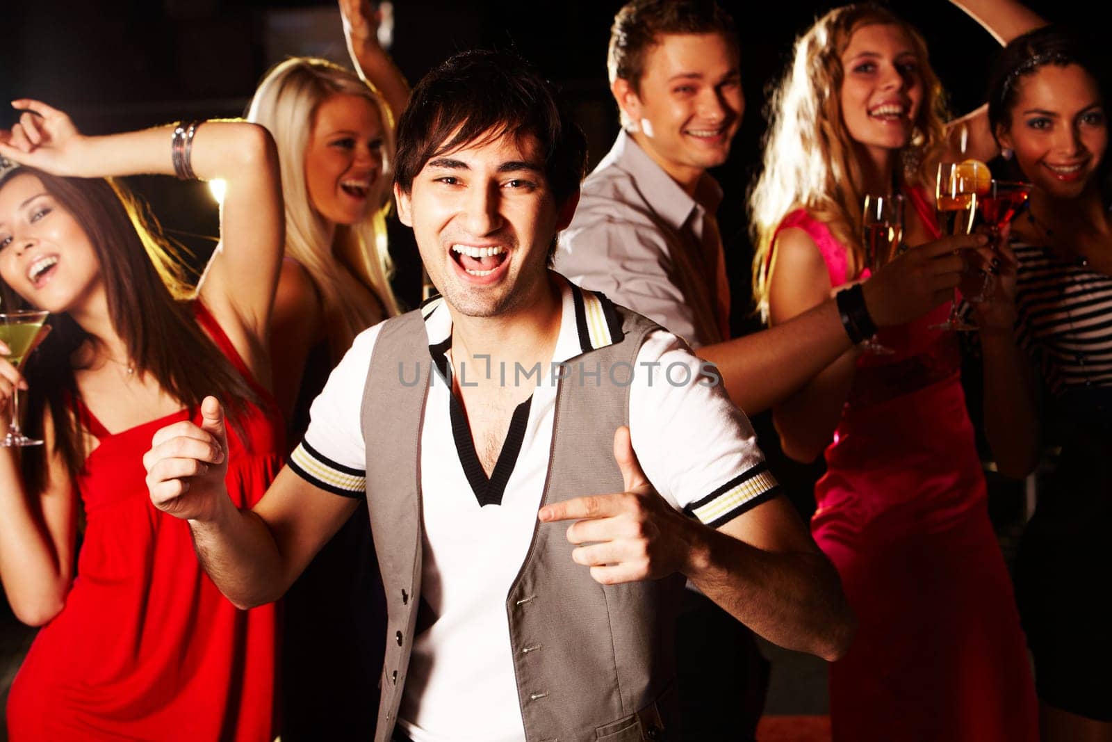 Portrait of energetic male dancing on background of happy friends