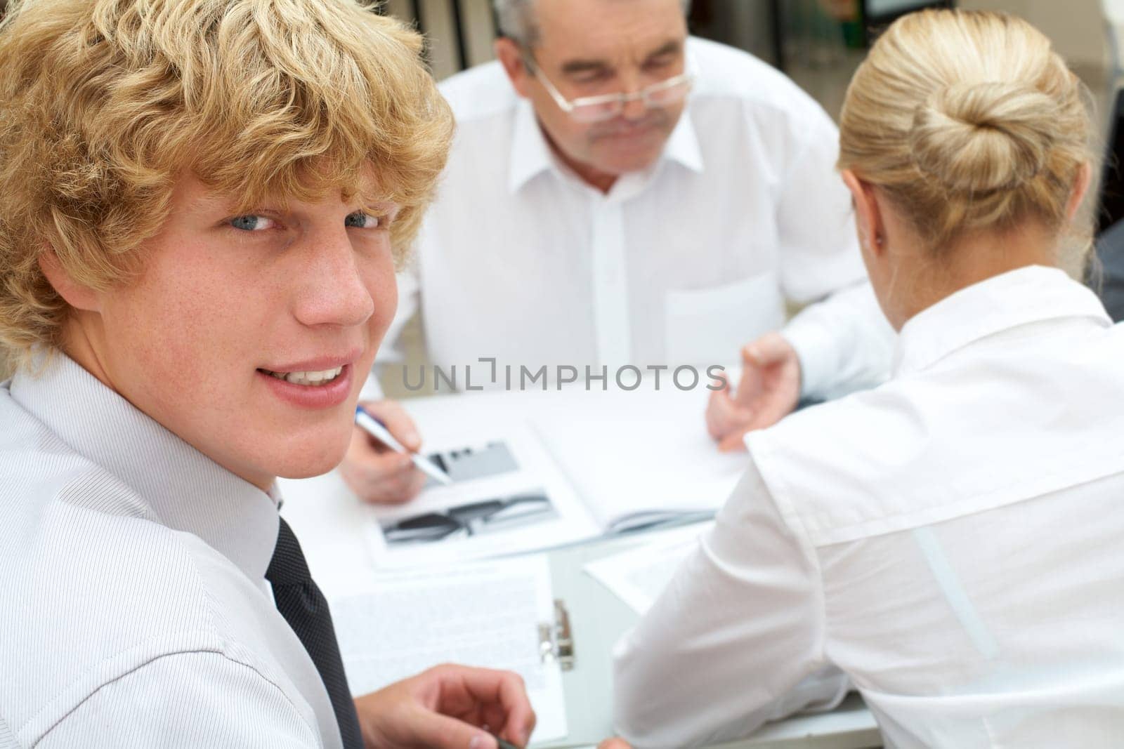 Portrait of confident businessman looking at camera with communicating partners at background