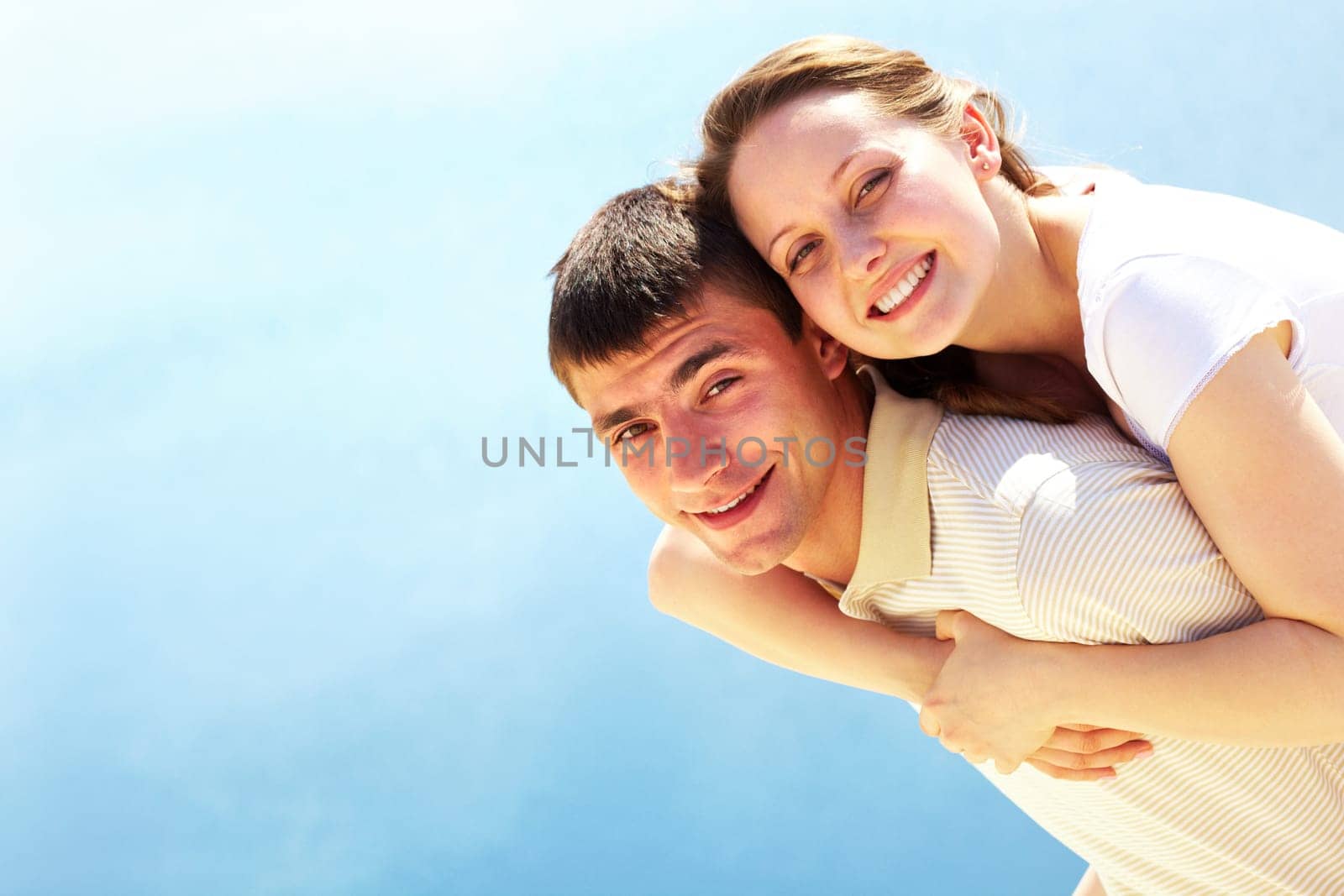 Photo of happy man giving piggyback to his girlfriend and both looking at camera