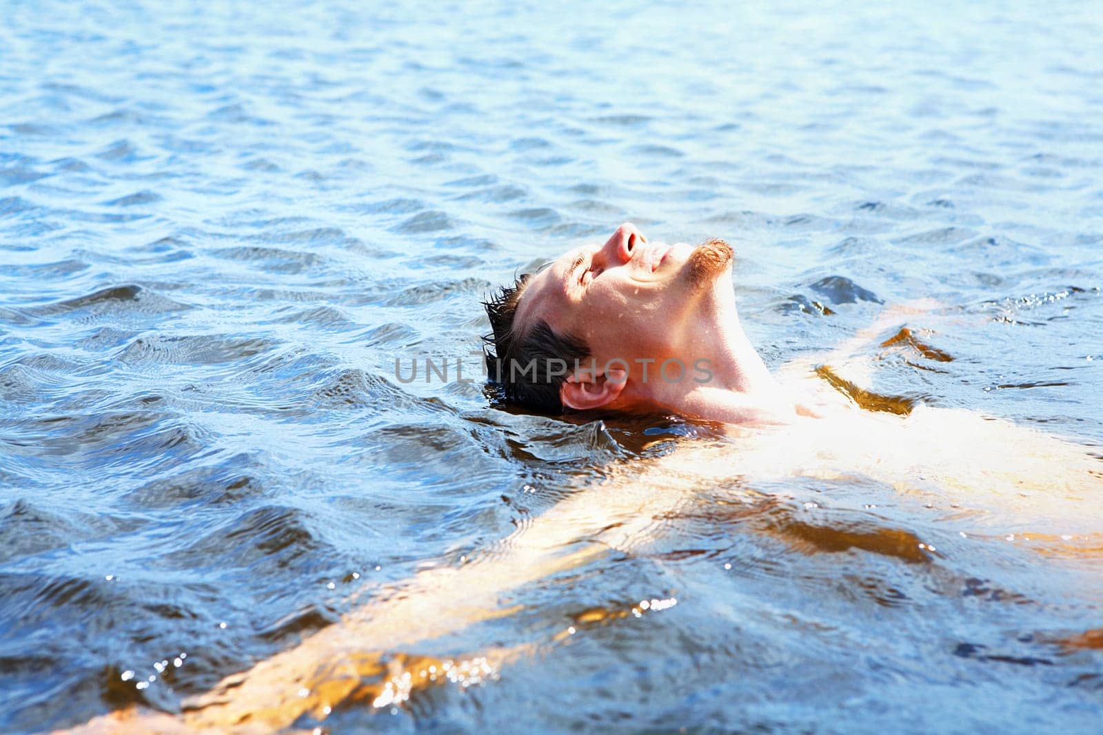 Delighted guy bathing in water and enjoying it