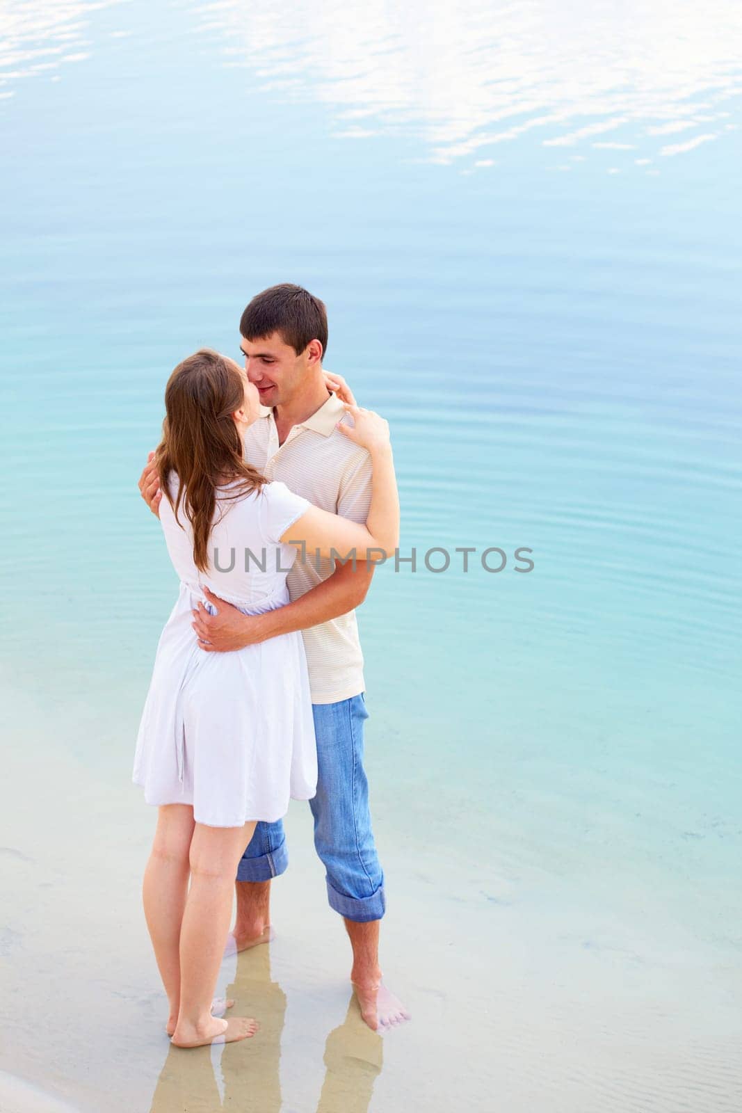 Photo of amorous couple standing in water enjoying summer vacation