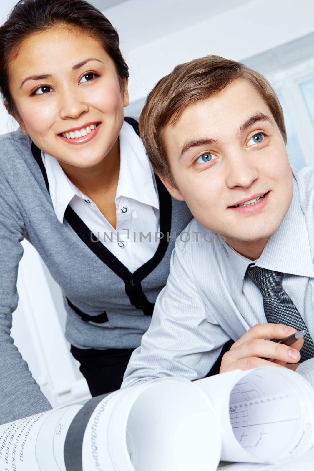 Successful colleagues looking aside with smiles during work