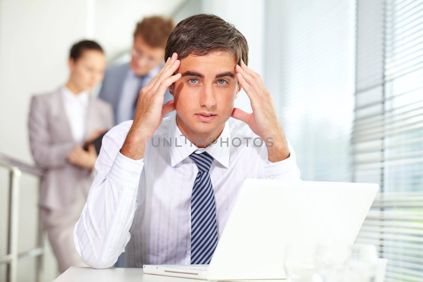 Stressed businessman sitting at table and looking at camera