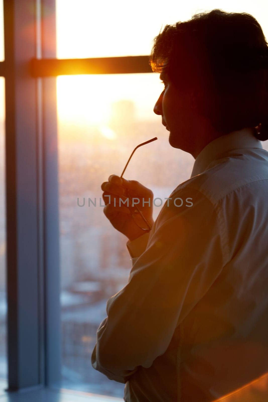 Portrait of pensive male thinking in office by the window