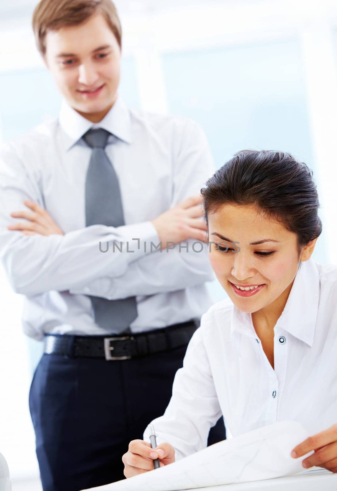 Portrait of pretty businesswoman reading document with her boss at background