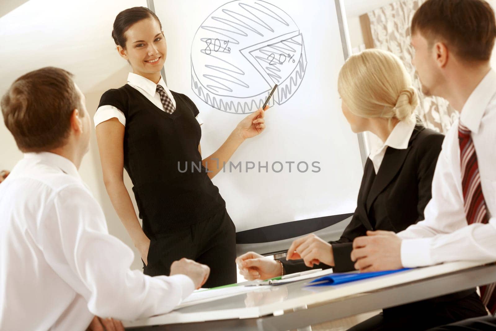 Photo of successful female standing by whiteboard while explaining her idea to colleagues