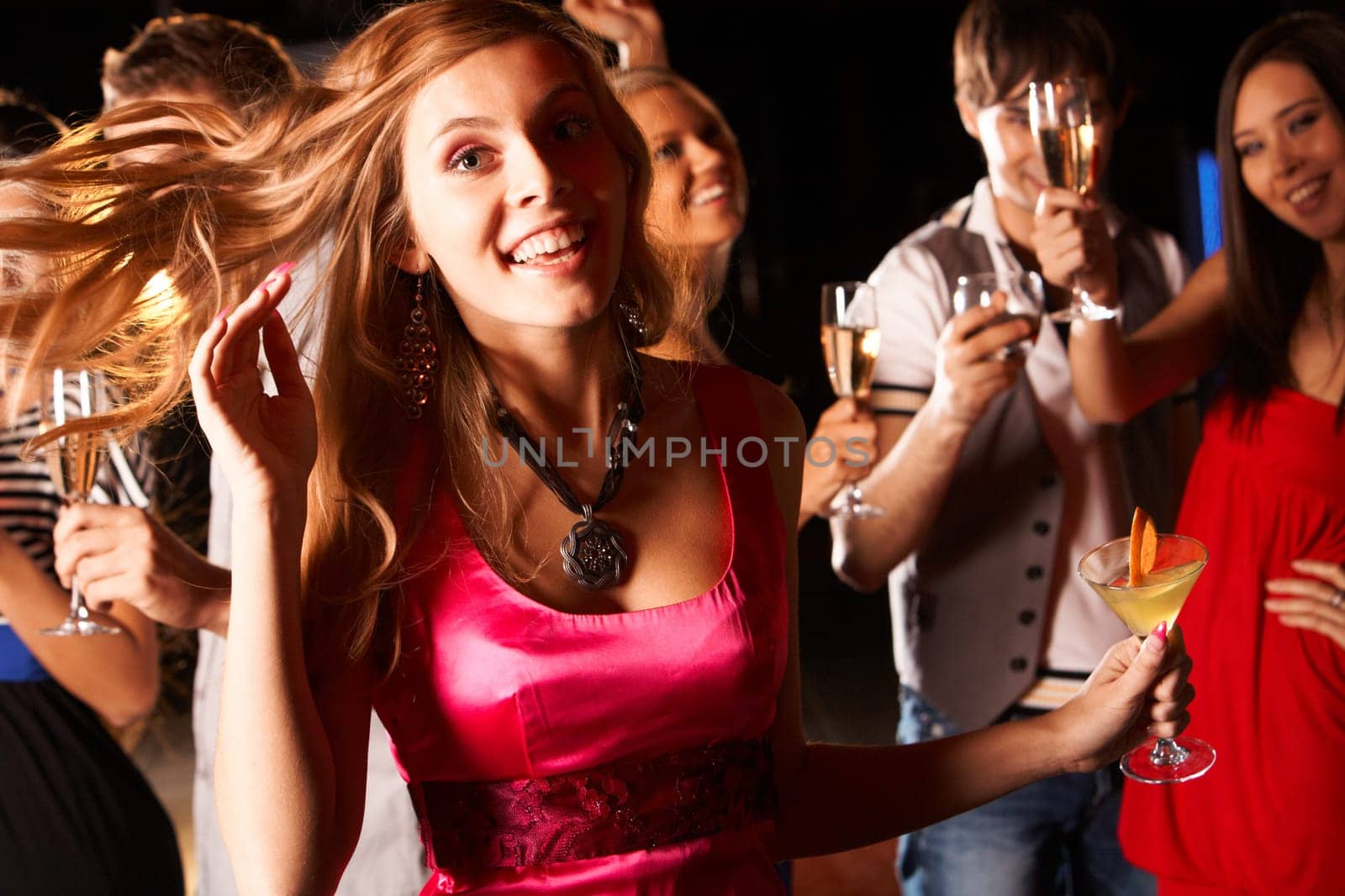 Portrait of cheerful girl with cocktail in hand having fun at discotheque