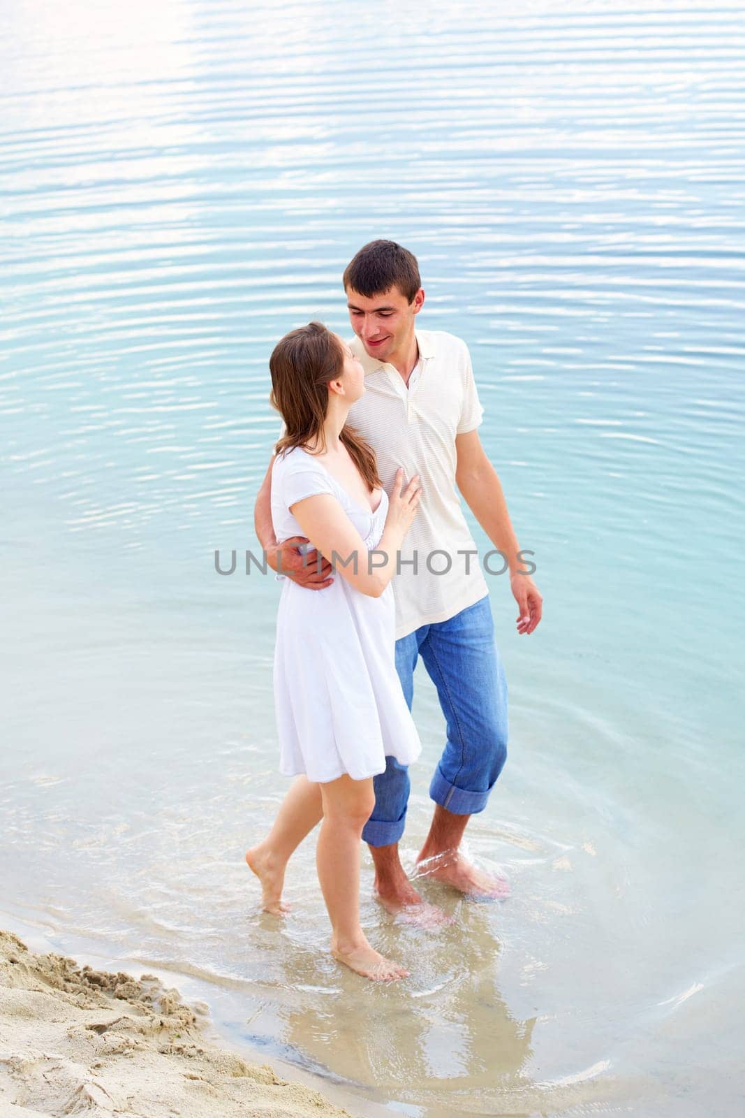 Photo of amorous couple walking in water on summer vacation