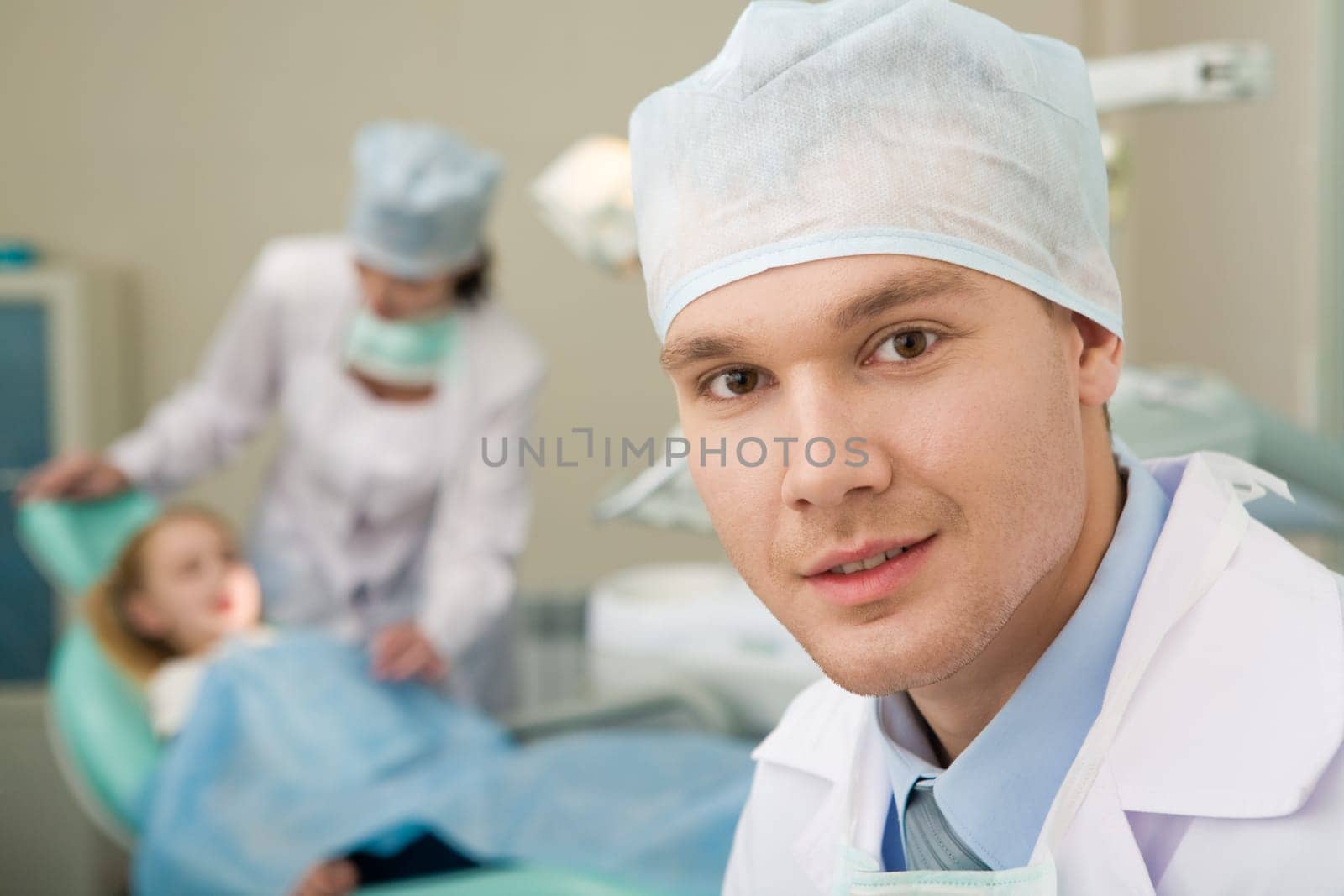 Portrait of confident doctor on background of his assistant with patient
