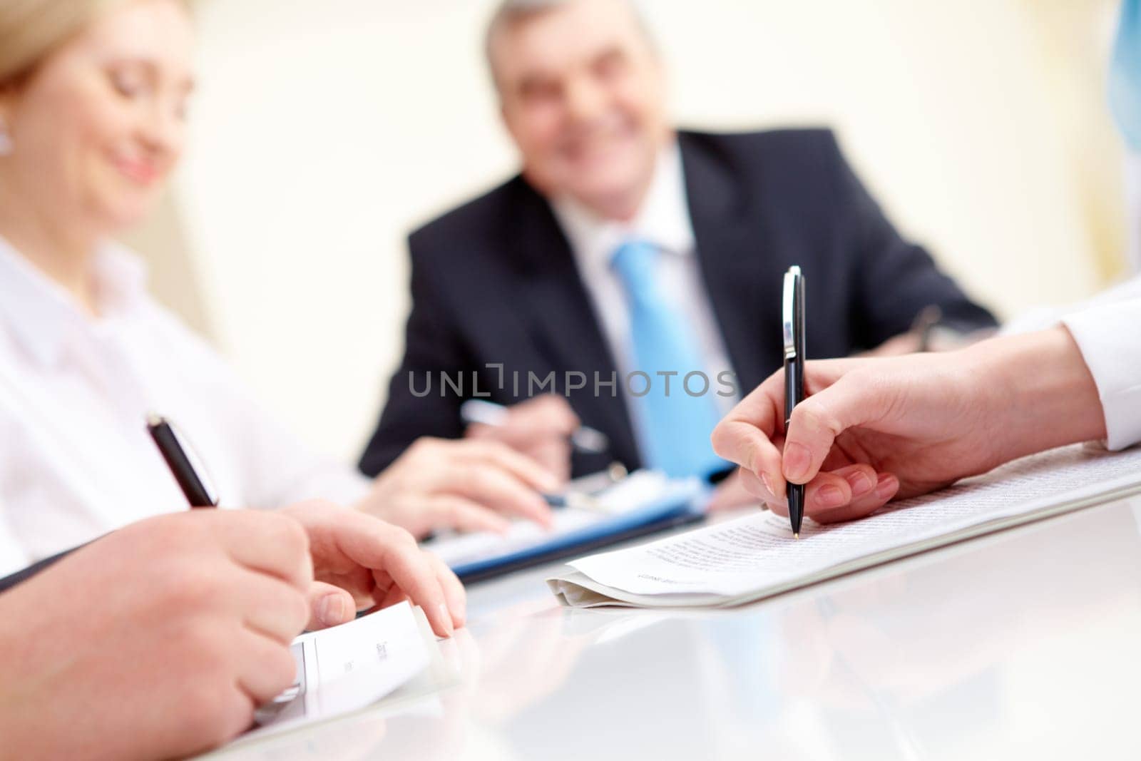 Close-up of business partners hands over document with their boss on background