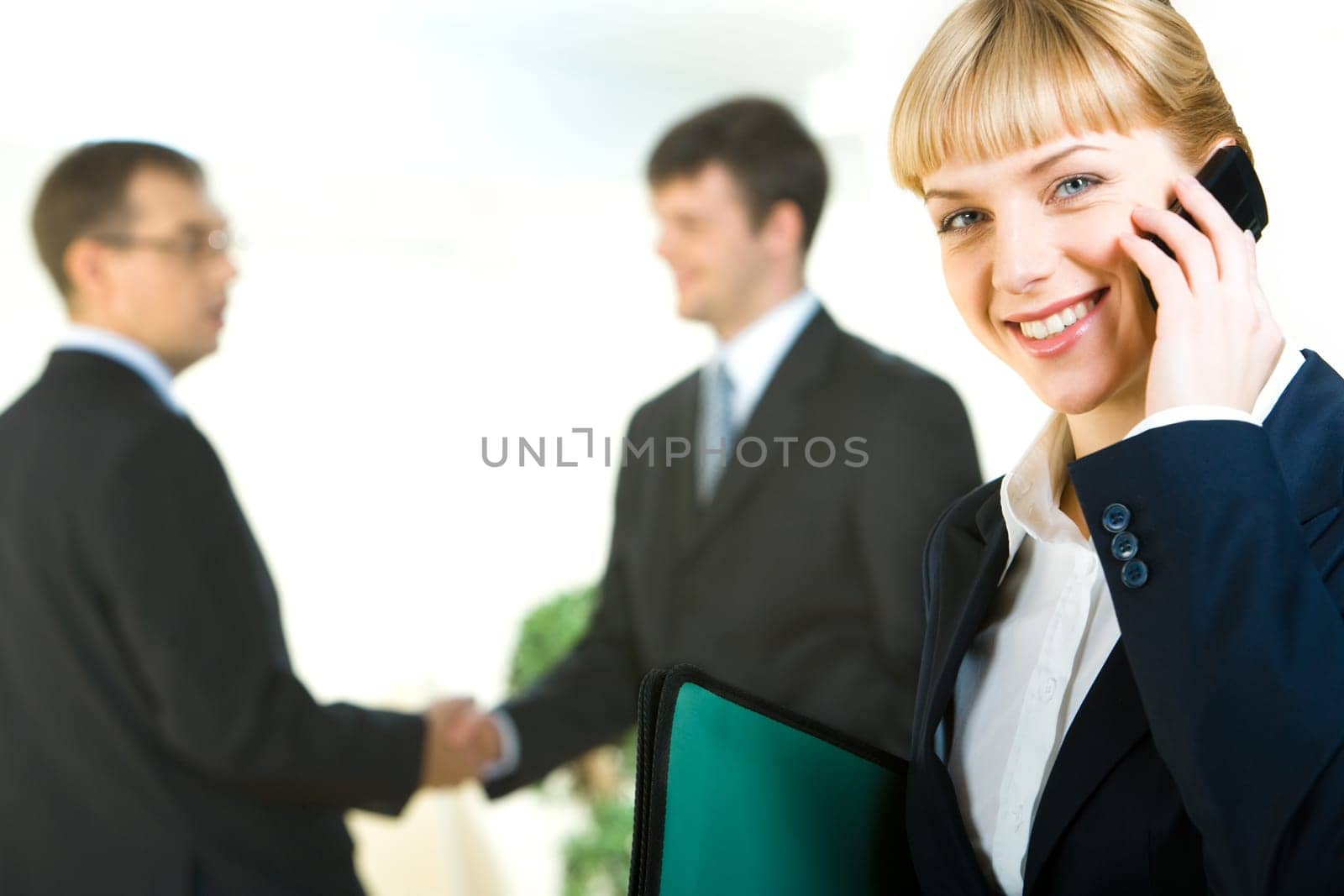 Portrait of business woman calling on the phone on the background of people shaking hands