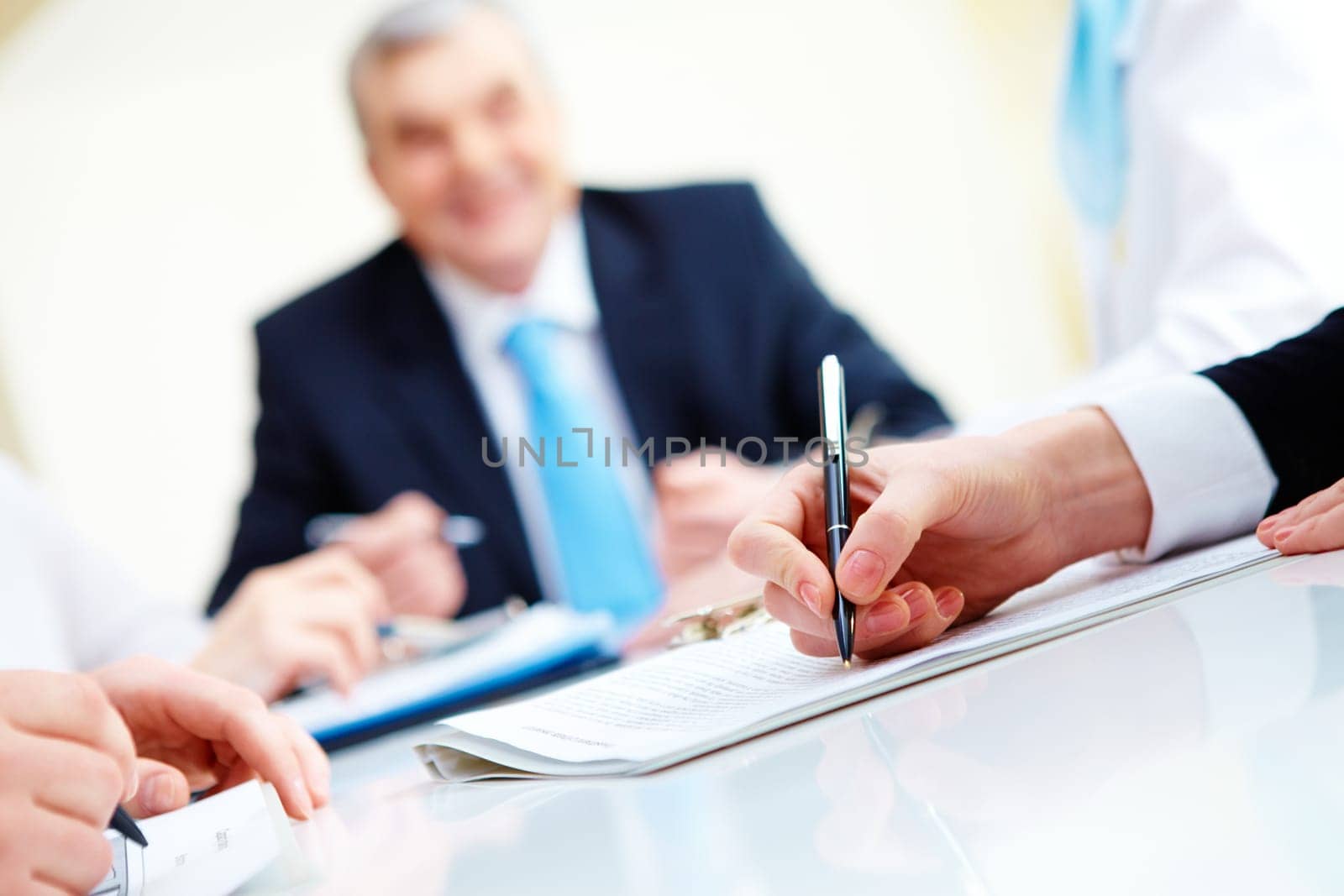 Close-up of secretary hands over document with her boss on background