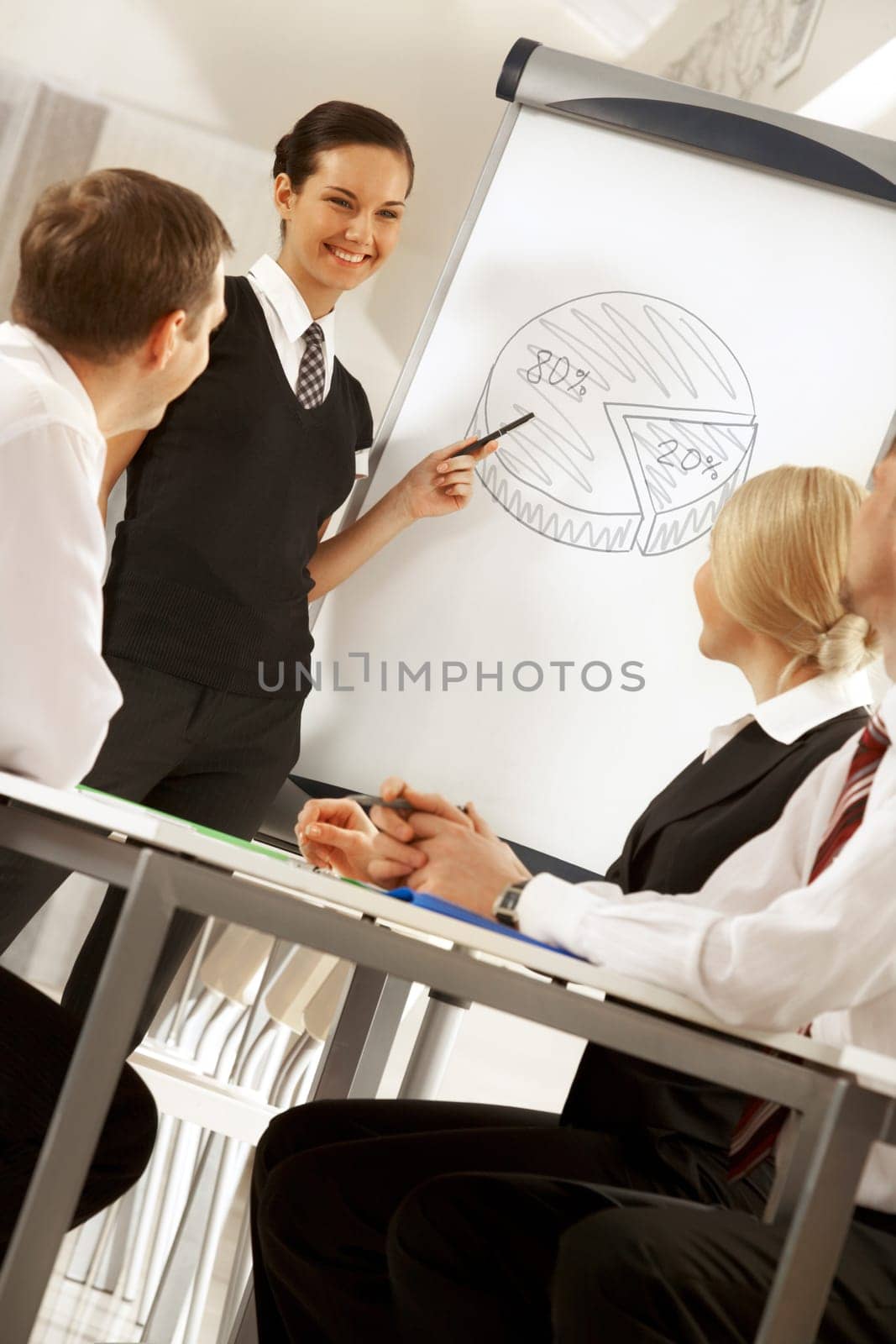 Photo of successful female standing by whiteboard while explaining her idea to colleagues