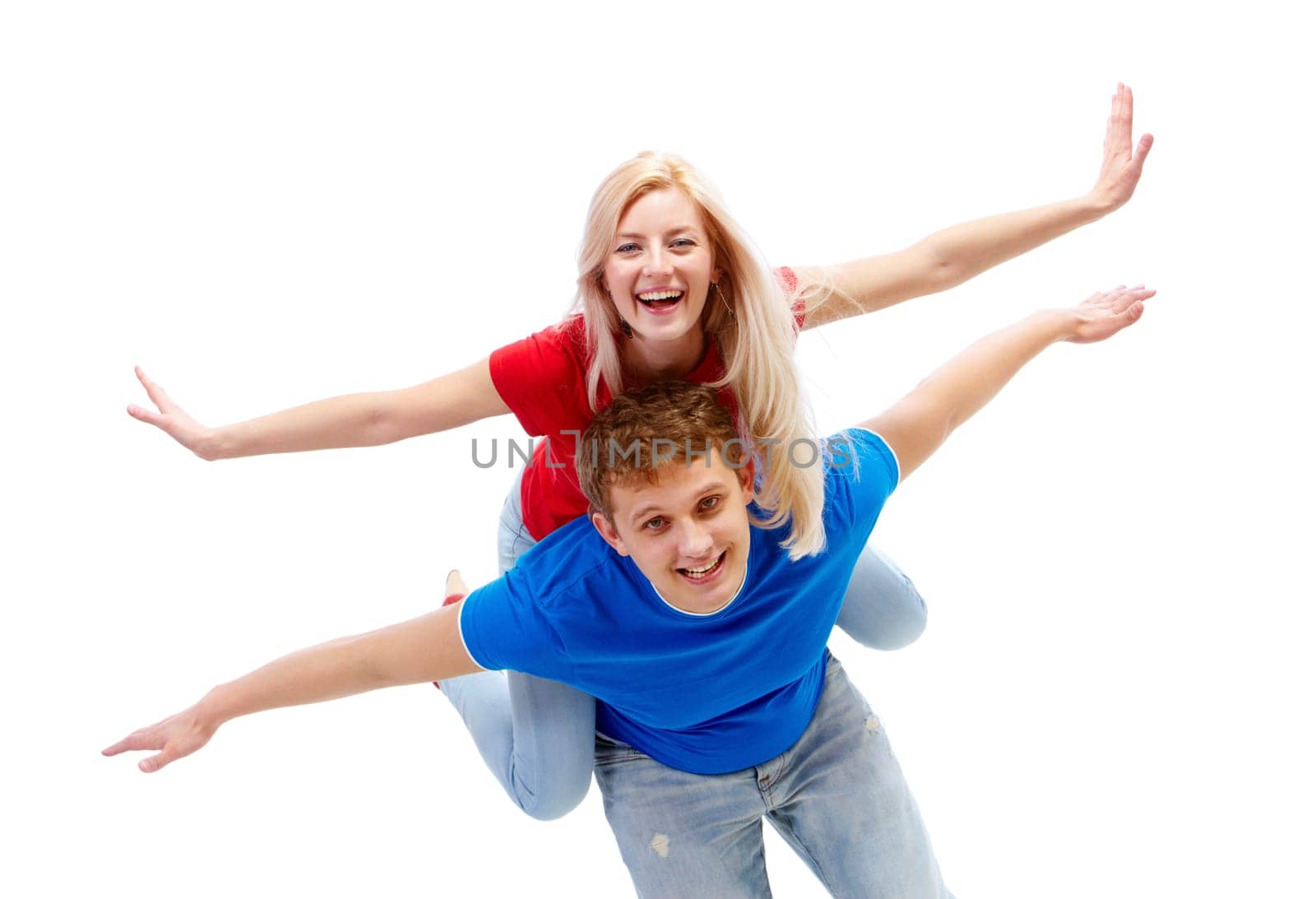 Photo of happy guy giving piggyback to joyful girl while both looking at camera