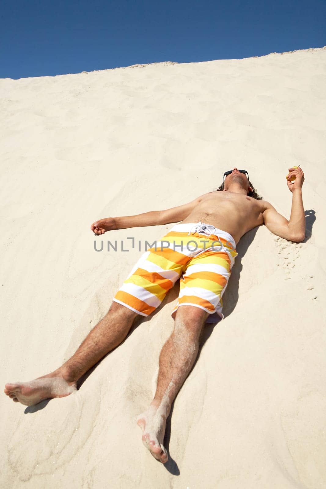 Happy guy lying on sandy beach and relaxing