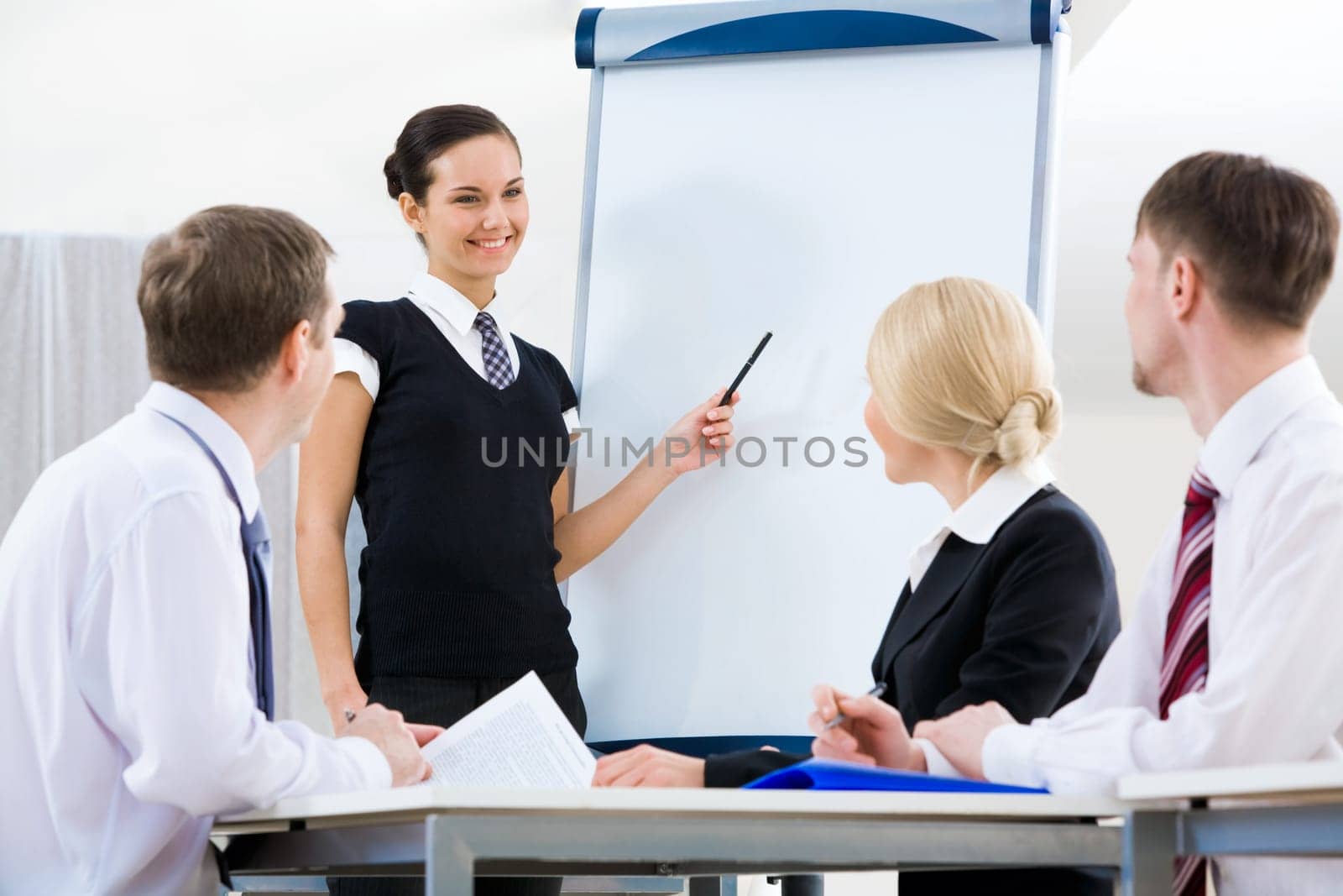 Photo of successful female standing by whiteboard while explaining her idea to colleagues