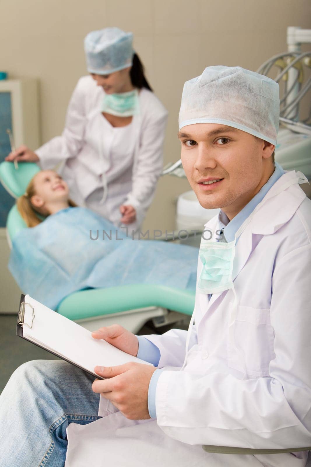 Image of sitting dentist with papers in hand looking at camera