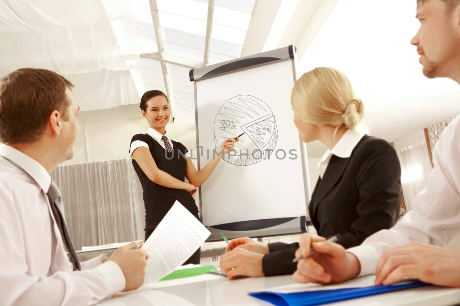 Photo of successful female standing by whiteboard and pointing at diagram on it at seminar