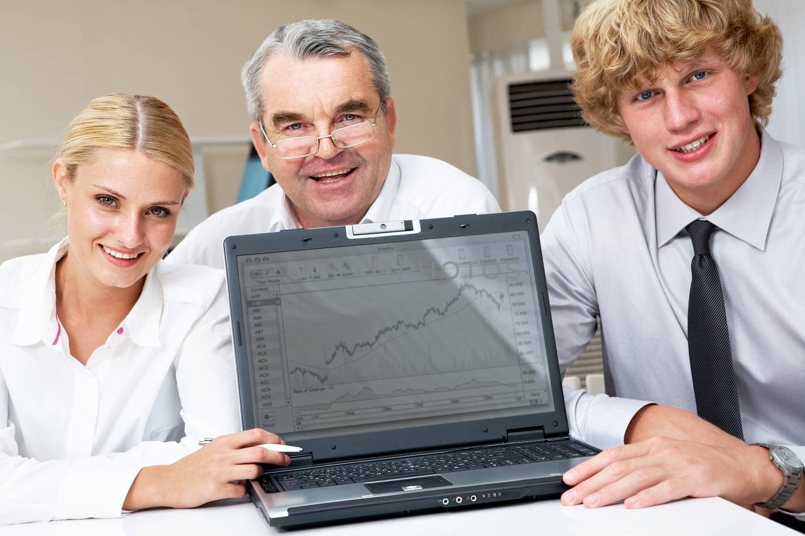 Portrait of positive business group sitting at the table with laptop on it