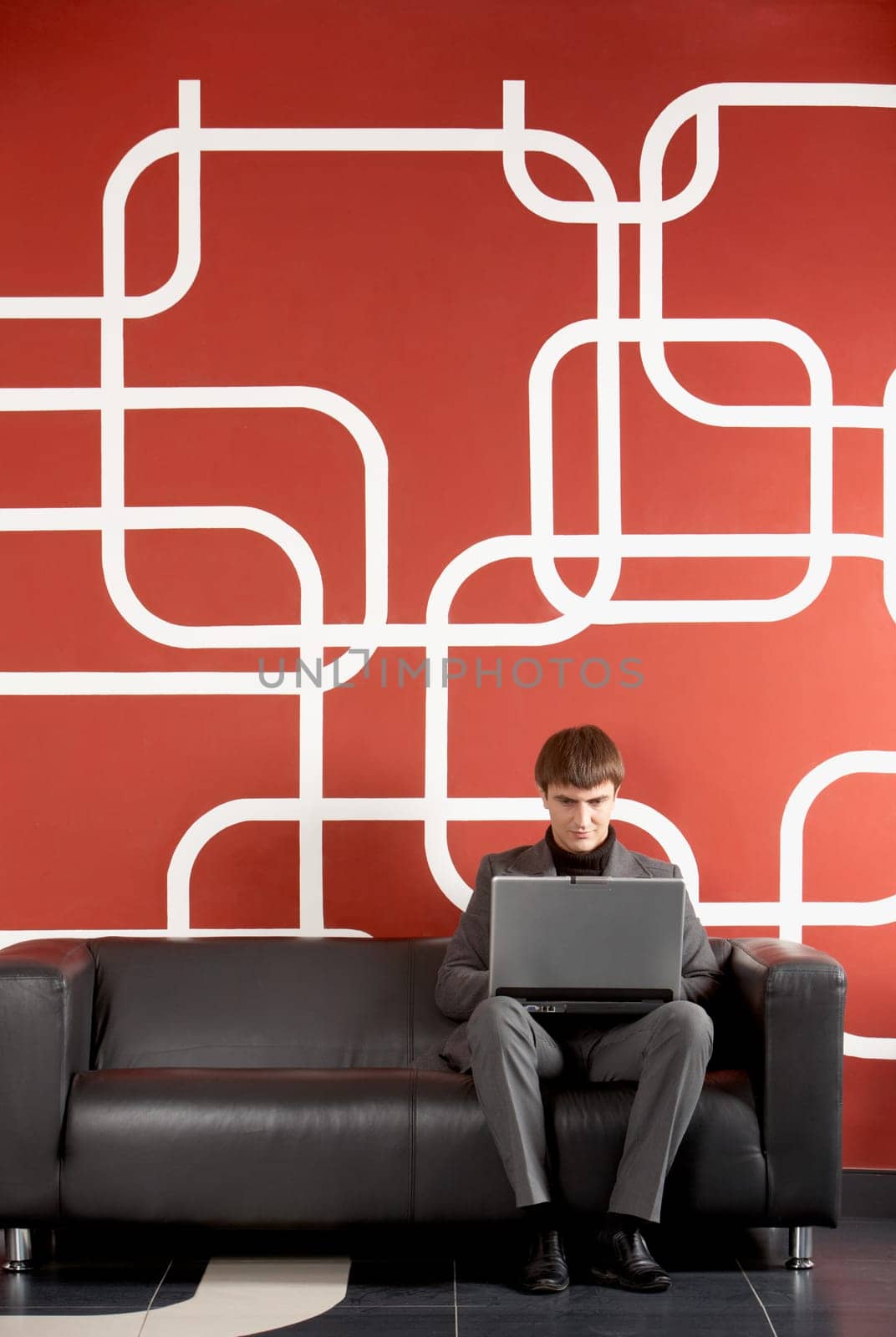 A businessman working on computer by the wall