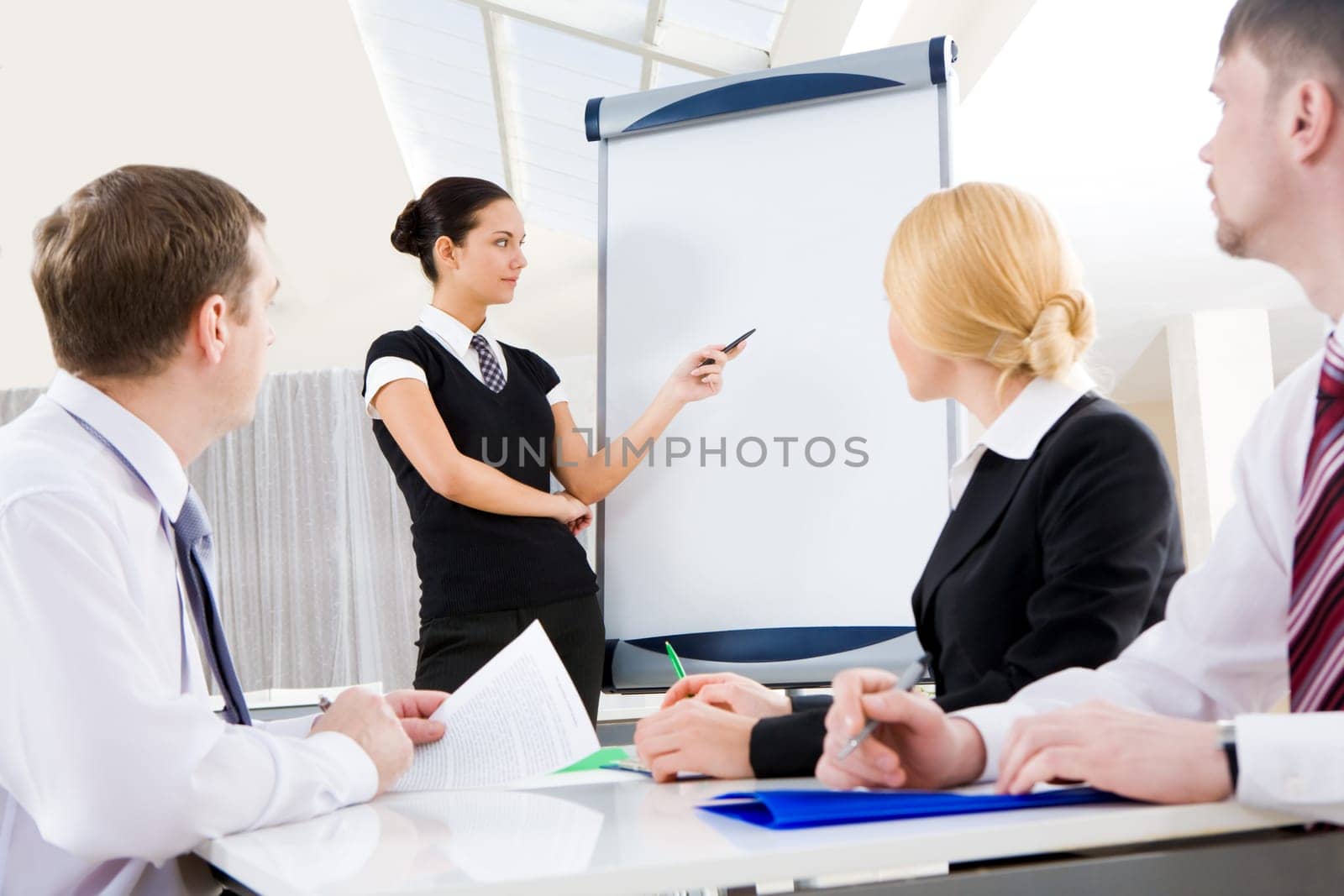 Smart and confident employee pointing at whiteboard while presenting her ideas