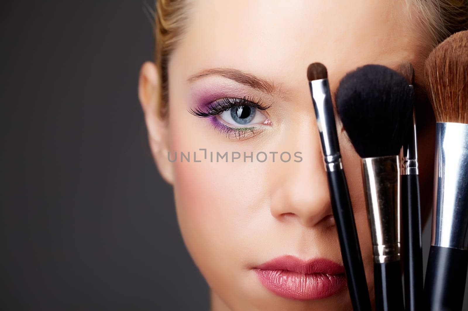 Close-up of young gorgeous female with brushes looking at camera