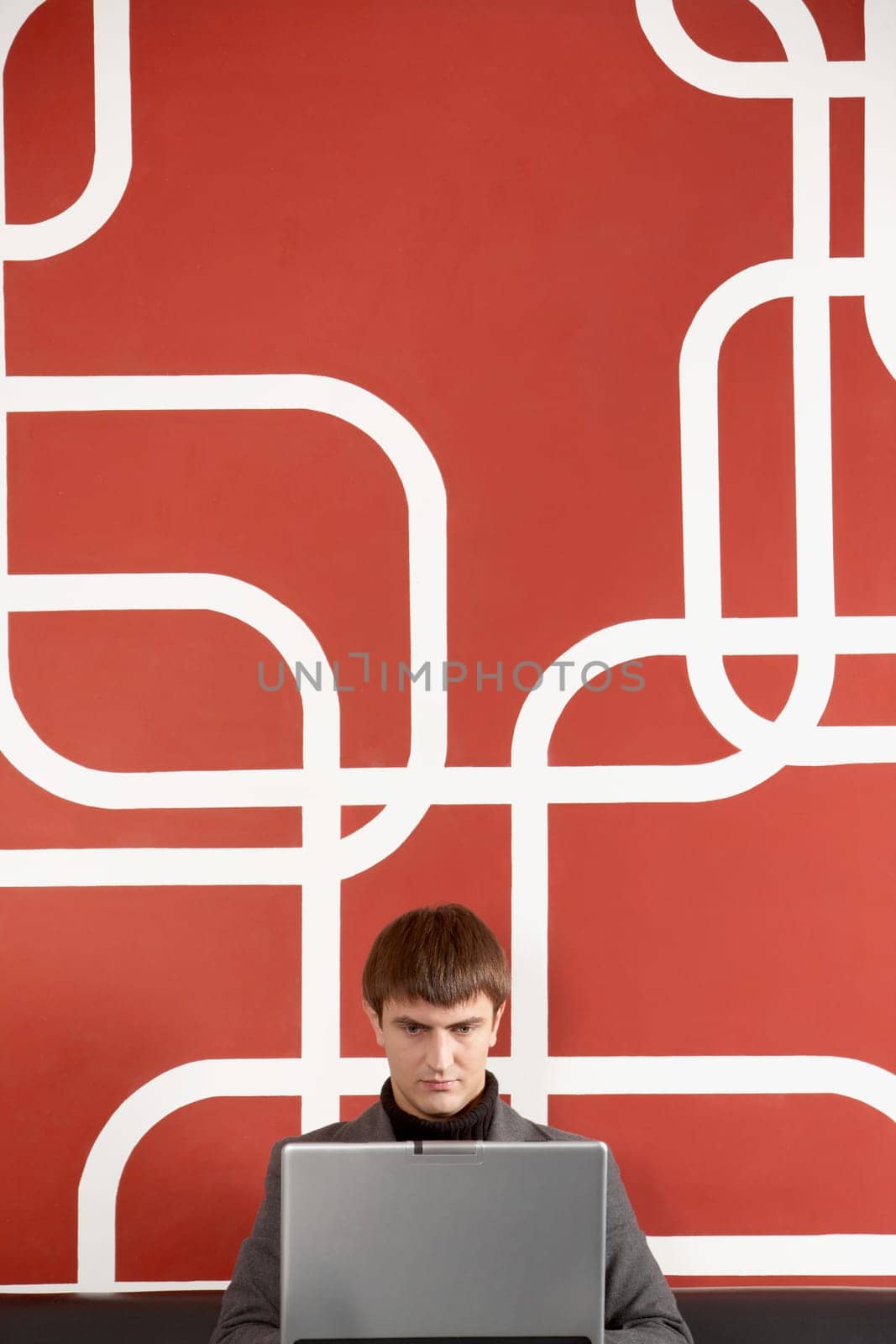 A businessman sitting by the wall concentrated on his laptop