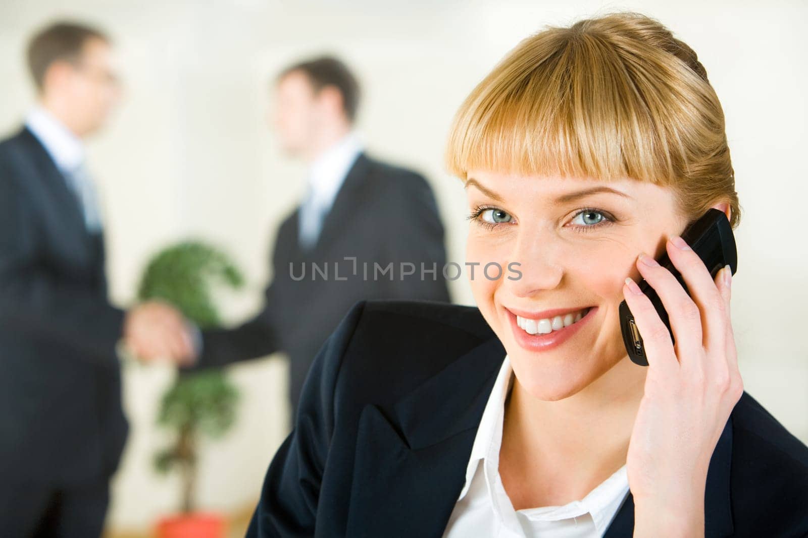View of attractive smiling businesswoman speaking on the mobile looking at camera