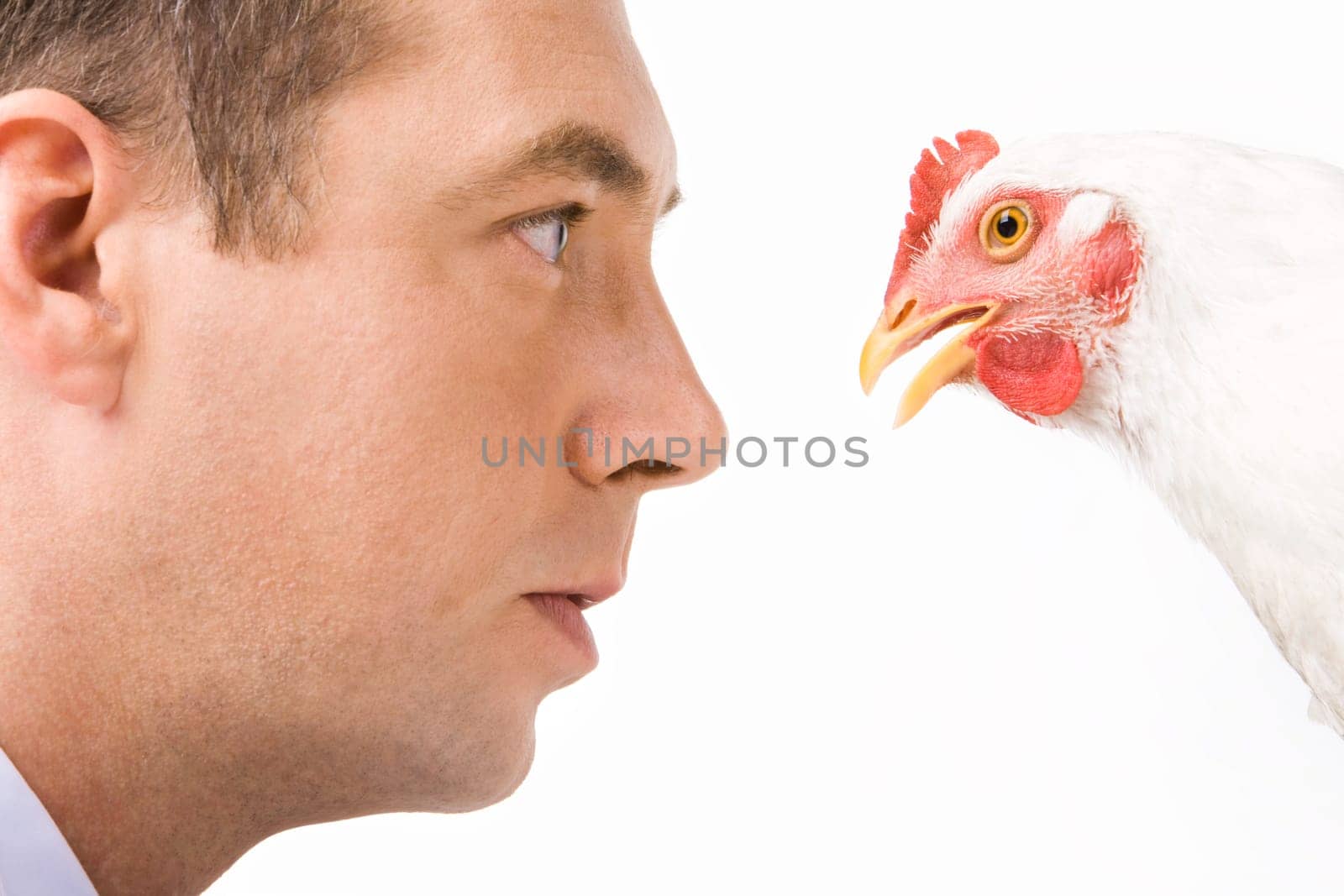 Close-up of serious male looking intently at chicken over white background