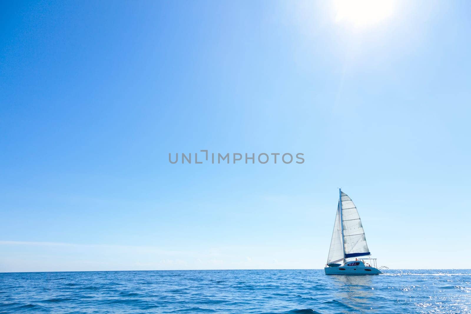 Lone sailboat in the open sea with bright sunny skies