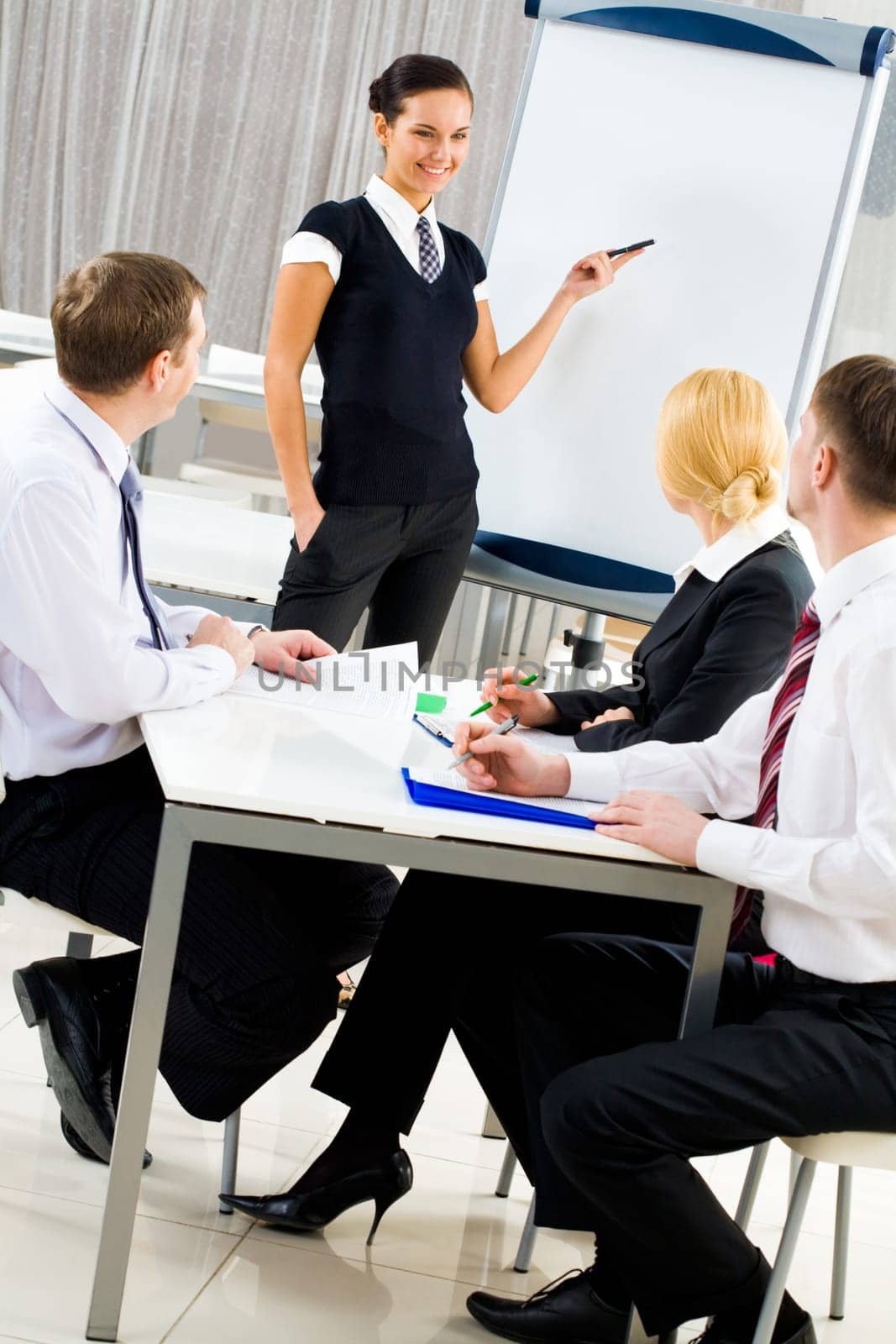 Smart and confident employee pointing at whiteboard while presenting her ideas