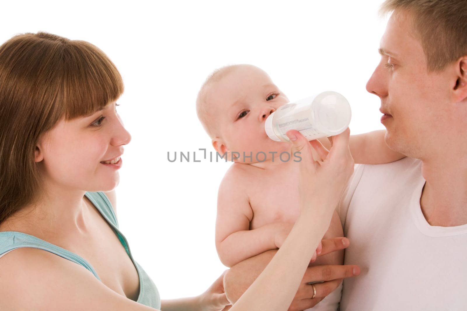Image of baby drinking milk from bottle in female hand while being held by father