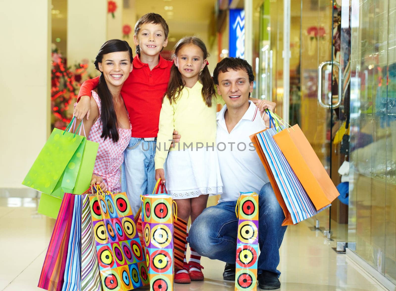 Portrait of a nice family of four with shopping bags looking at camera and smiling