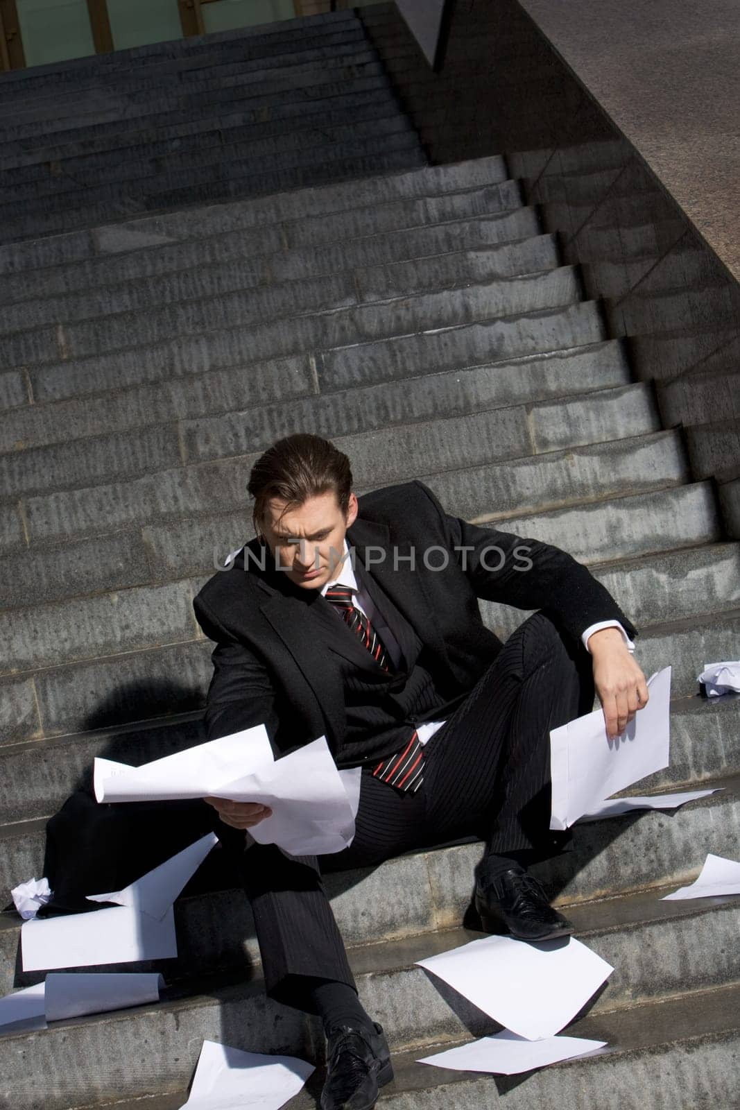 Image of frustrated man sitting with papers in hands and reading them