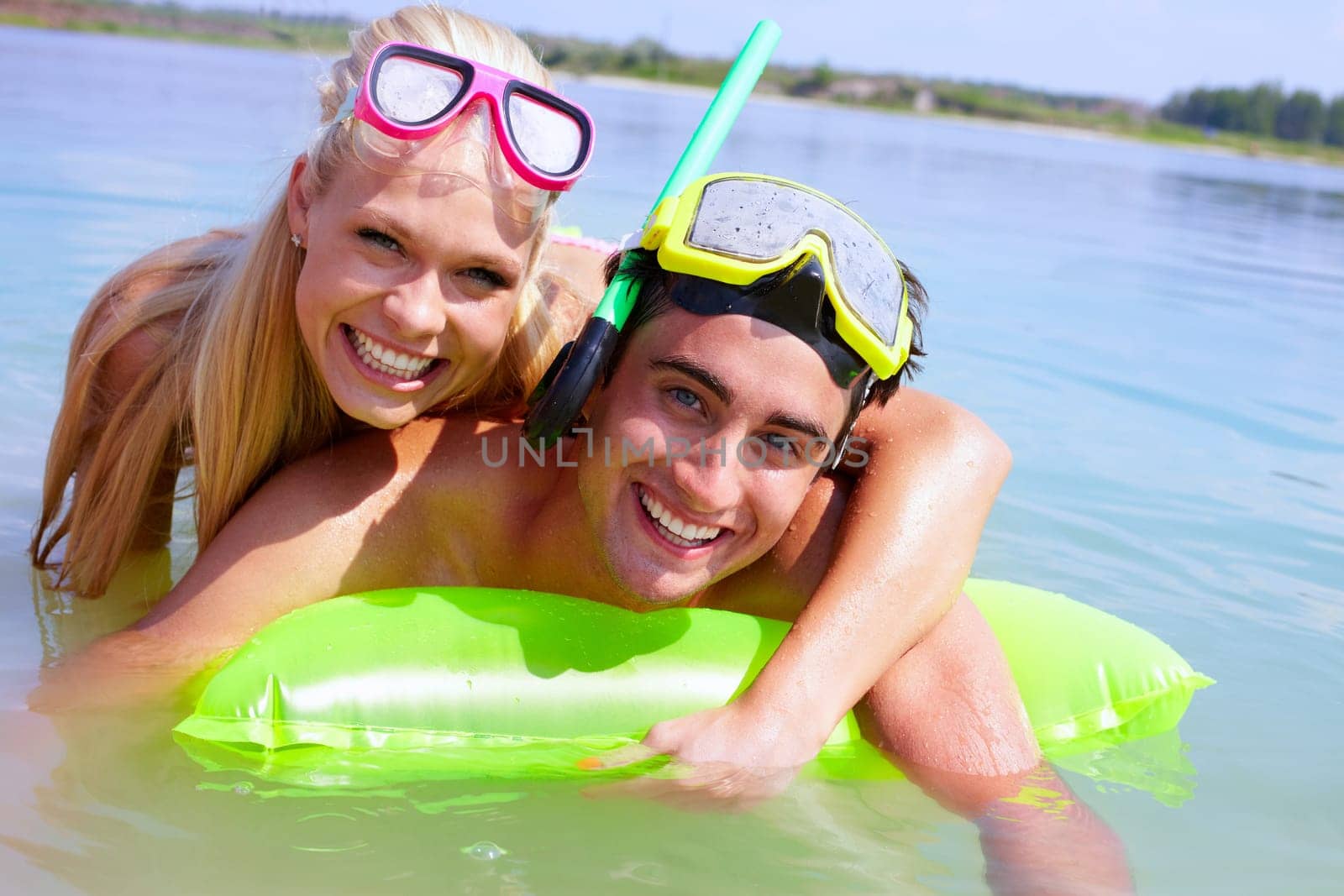 A young couple on lilo looking at camera and smiling