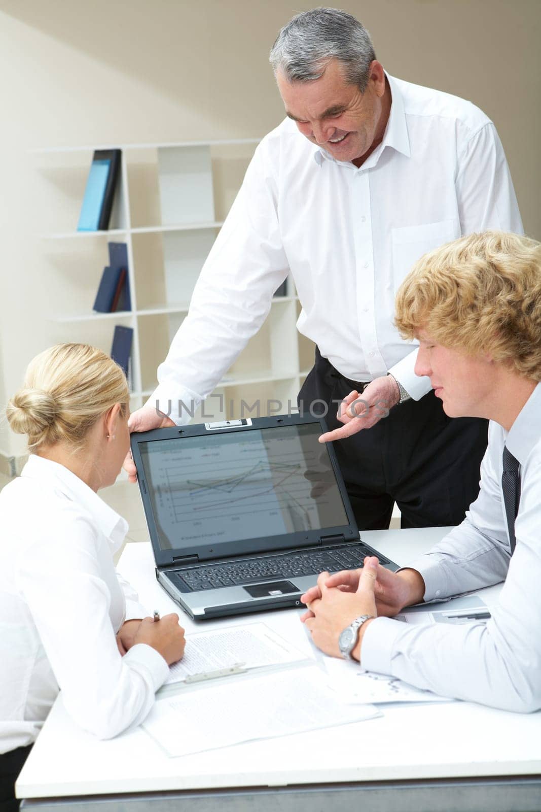 Image of senior boss presenting computer work to young partners