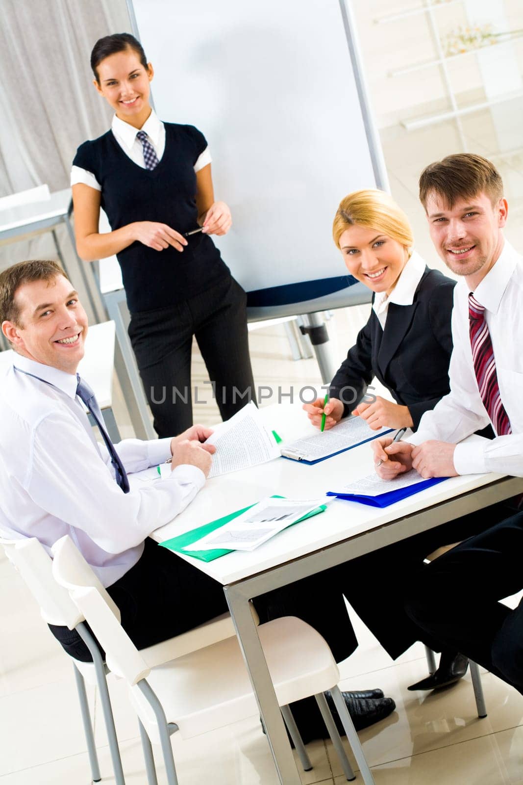 Portrait of executive business group sitting at table and smiling at camera with smart teacher on background