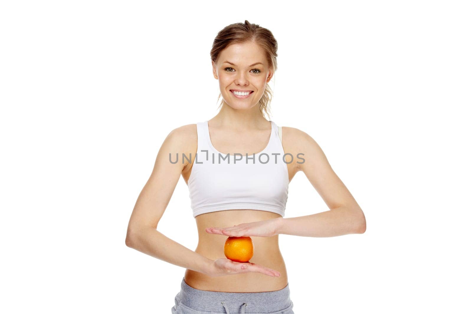 Image of young healthy woman holding an orange in front of belly