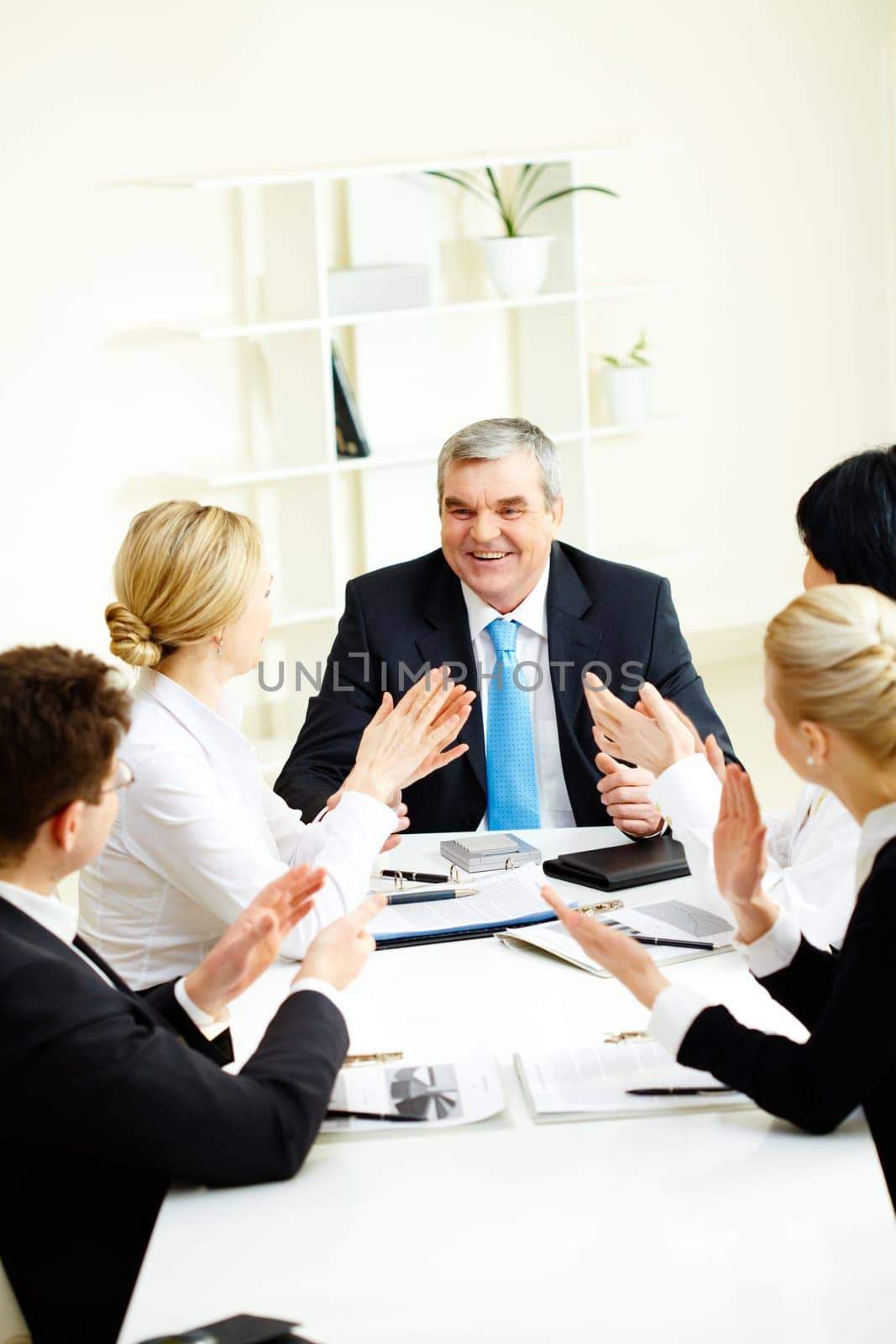 Image of senior leader surrounded by his colleagues applauding to him