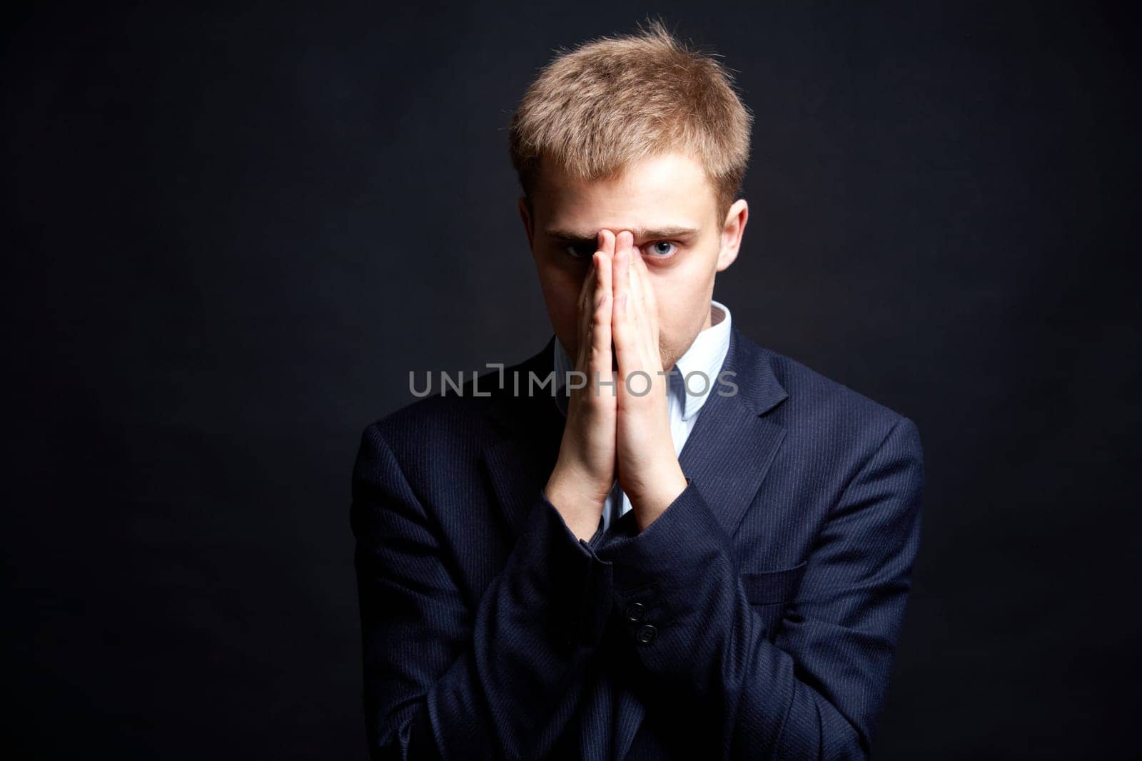 Portrait of stylish businessman looking at camera with hands by his face